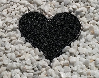 May include: A black heart-shaped cutout in a bed of white gravel.
