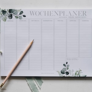 Könnte beinhalten: Ein weißer Wochenplaner mit dem grauen Titel "WOCHENPLANER" und dem Text "AUFGABEN, TRAUME, KAFFEE-DATES". Der Planer hat sieben Spalten für jeden Tag der Woche, wobei die Tage auf Deutsch beschriftet sind. Der Planer hat ein florales Design mit grünen Blättern und weißen Blüten am unteren Rand.