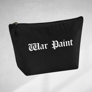 Può includere: Pochette nera in tela con cerniera e scritta bianca "War Paint" in font gotico.