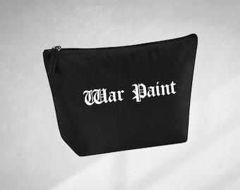 Op de afbeelding: Zwarte canvas toilettas met witte tekst "War Paint" in gotische letter.