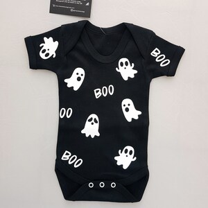 May include: Black baby onesie with white ghost and "BOO" graphics.