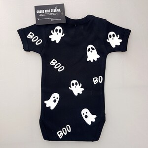 May include: Black baby onesie with white ghost and "BOO" designs. The onesie is made by Chaos Kids Club GB.