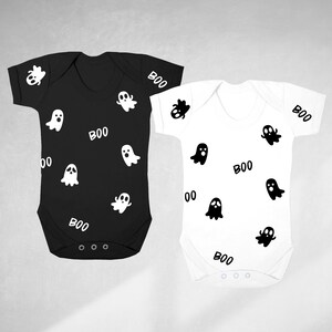 May include: Two baby onesies, one black and one white, with a ghost and "BOO" pattern.