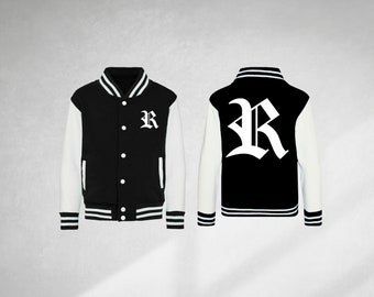 Op de afbeelding: Zwart-witte varsity jas met een grote witte letter "R" op de rug en een kleinere witte letter "R" op de linker borst. De jas heeft witte mouwen en zwart-witte strepen rond de manchetten en de onderkant.