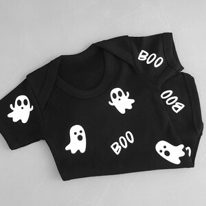 May include: Black baby onesie with white ghost and "BOO" designs.