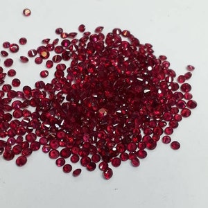 Puede incluir: Un montón de piedras preciosas de rubí rojo sueltas sobre un fondo blanco.