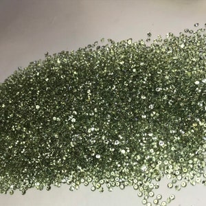 May include: A large pile of small, round, light green gemstones.