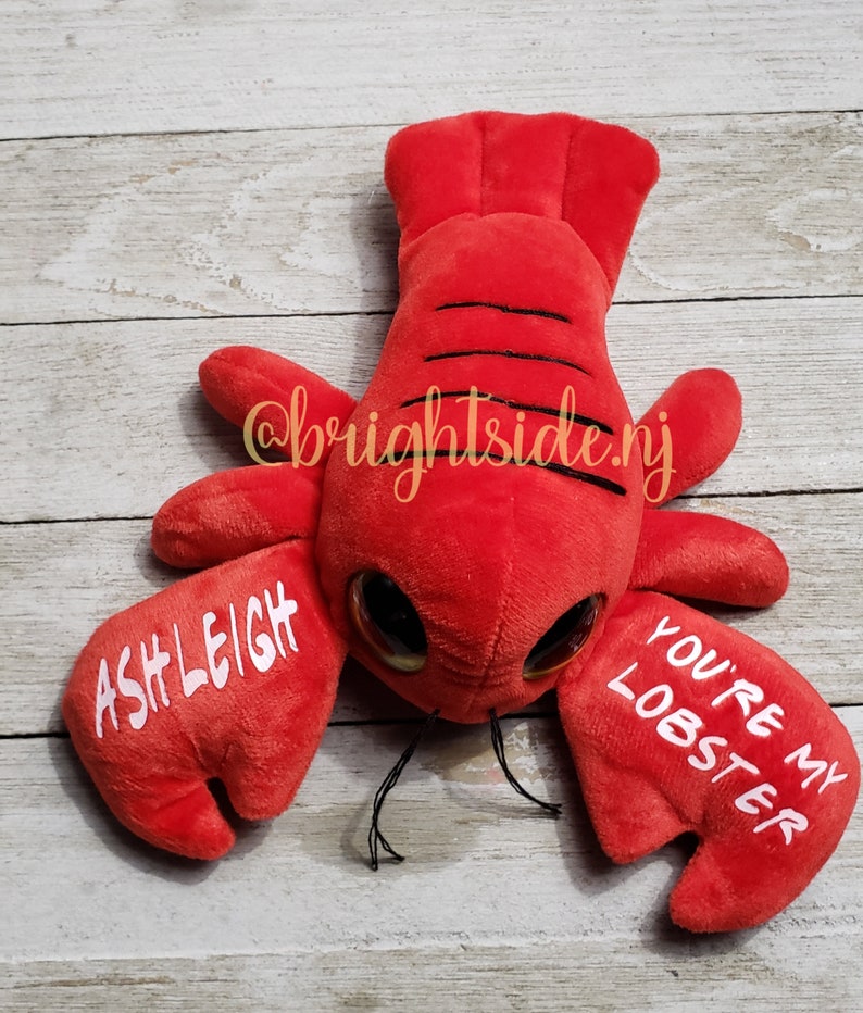 K&ouml;nnte beinhalten: Rotes Pl&uuml;sch-Hummer-Spielzeug mit Glitz Augen und dem Text "You're my lobster" und "Ashleigh" auf den Scheren.