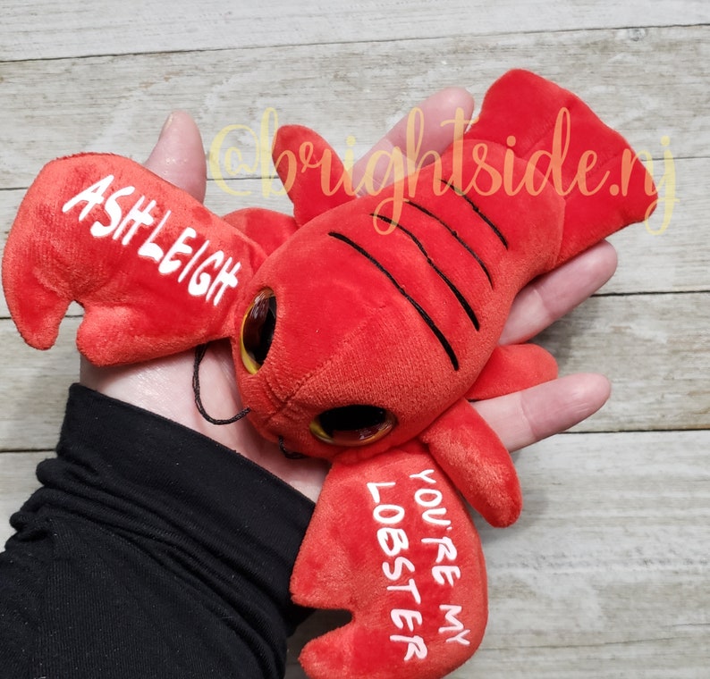 K&ouml;nnte beinhalten: Rotes Pl&uuml;sch-Hummer-Spielzeug mit Glitz Augen und dem Text "You're my lobster" und "Ashleigh" auf den Scheren.