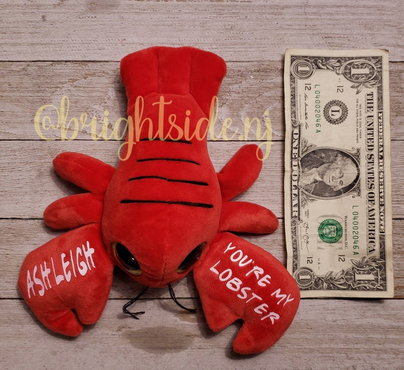 K&ouml;nnte beinhalten: Rotes Pl&uuml;sch-Hummer-Spielzeug mit Glitz Augen und dem Text "You're my lobster" und "Ashleigh" auf den Scheren.