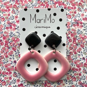 May include: A pair of pink ceramic earrings with black ceramic squares hanging from them. The earrings are displayed on a white card with black polka dots and the text "MariMo céramique".