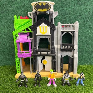 Peut inclure: Un ensemble de jeu Batman à plusieurs niveaux avec un Bat-Signal, une grue verte et un ascenseur violet. Il comprend des figurines de Batman, Catwoman, le Joker et d'autres personnages. L'ensemble est en plastique.