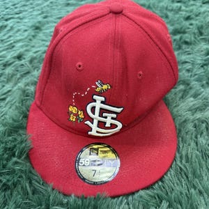 Könnte beinhalten: Rote Baseballkappe mit gebogenem Schirm. Die Kappe hat ein weißes "STL"-Logo mit einem Bienen- und Blumenmuster. Größe 7 1/4.