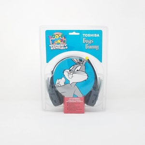 May include: A new, boxed Toshiba LT200BUG AM/FM stereo headphone radio featuring Bugs Bunny from Looney Tunes. The packaging is clear plastic with a blue and white graphic of Bugs Bunny. The box also includes the Looney Tunes Tronics logo.