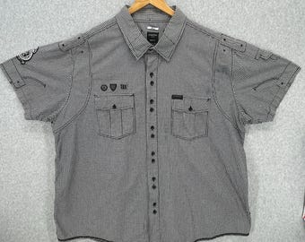 May include: Black and white checkered button-down shirt with short sleeves and a pocket on the left chest. The shirt has a black embroidered design on the pocket.