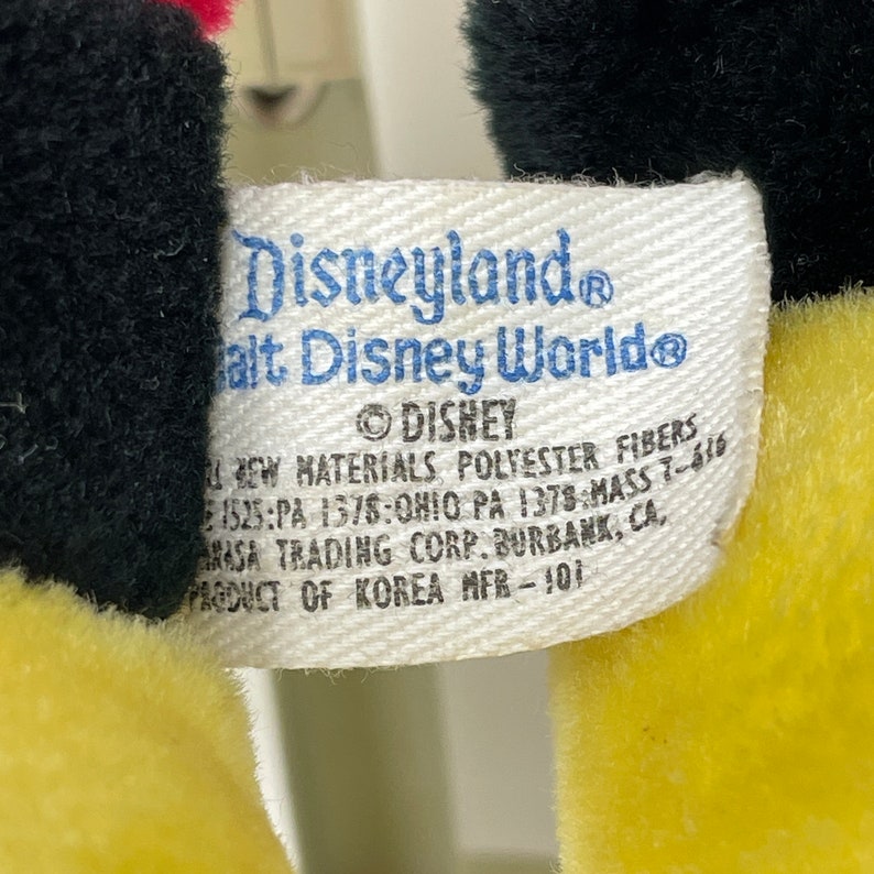 May include: White tag with black text that reads "Disneyland Walt Disney World&reg; &copy;DISHEY All New Materials Polyester Fibers 1525:PA 1378:OHIO PA 1378:MASS 7-610 Masa Trading Corp. Burbank, CA, Product of Korea MFR-101"