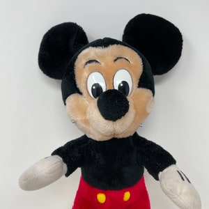 May include: A black and red plush Mickey Mouse toy with large black ears and white eyes. The toy has a black nose and a red mouth.