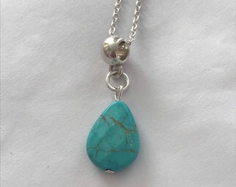 Puede incluir: Un collar de cadena de plata con un colgante de lágrima turquesa.