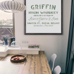 K&ouml;nnte beinhalten: Ein gerahmter Druck mit einem Vintage-Design f&uuml;r Griffin Irish Whiskey. Der Text lautet "Griffin Irish Whiskey, Destilliert und abgef&uuml;llt von Seamus Griffin & Sons, Dawson St., Dublin, Irland, Gegr&uuml;ndet seit 1787".