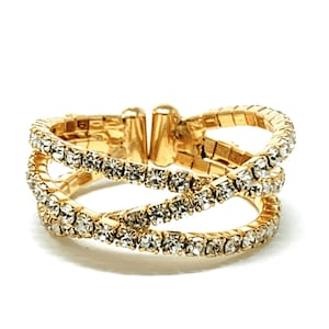 May include: A gold ring with three rows of clear rhinestones. The ring is adjustable and has a delicate, feminine design.