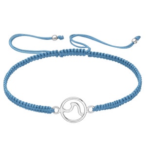 May include: A blue braided cord bracelet with a silver charm featuring a wave design.