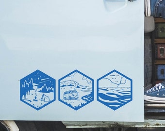 May include: Three blue hexagonal stickers with illustrations of outdoor scenes. The first sticker shows a forest with a tent and a campfire. The second sticker shows a van driving on a beach with cliffs in the background. The third sticker shows a blue ocean with waves.