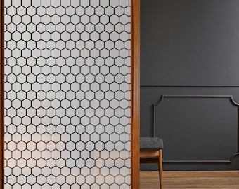 May include: A frosted glass door with a wood frame and a honeycomb pattern. The door is partially open, revealing a dark gray wall with a chair and a wood floor.