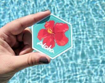 May include: A hexagonal sticker with a red hibiscus flower and the word "Aloha" in white lettering on a turquoise background.