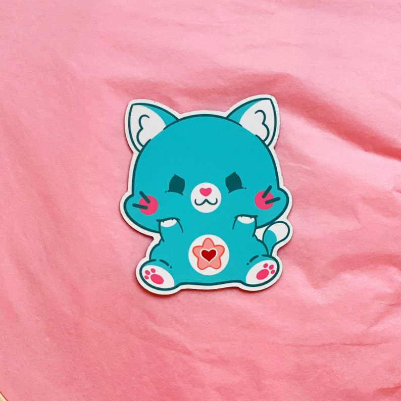 K&ouml;nnte beinhalten: Ein blauer Katzenaufkleber mit einem rosa Herzen auf der Brust. Die Katze hat einen wei&szlig;en Stern auf der Brust und l&auml;chelt.
