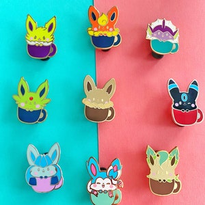 May include: Nine enamel pins featuring different Pokemon characters in a mug. The Pokemon are Eevee, Flareon, Jolteon, Vaporeon, Espeon, Umbreon, Glaceon, Leafeon, and Sylveon. The mugs are all different colors and have a white rim.