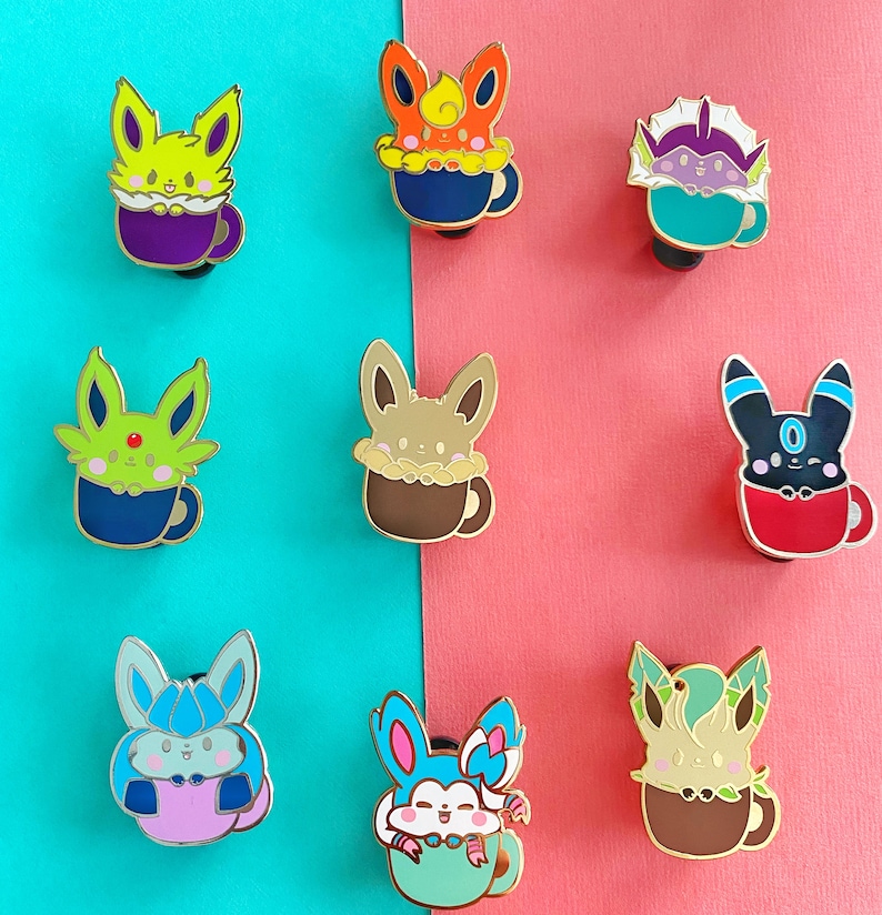 May include: Nine enamel pins featuring different Pokemon characters in a mug. The Pokemon are Eevee, Flareon, Jolteon, Vaporeon, Espeon, Umbreon, Glaceon, Leafeon, and Sylveon. The mugs are all different colors and have a white rim.