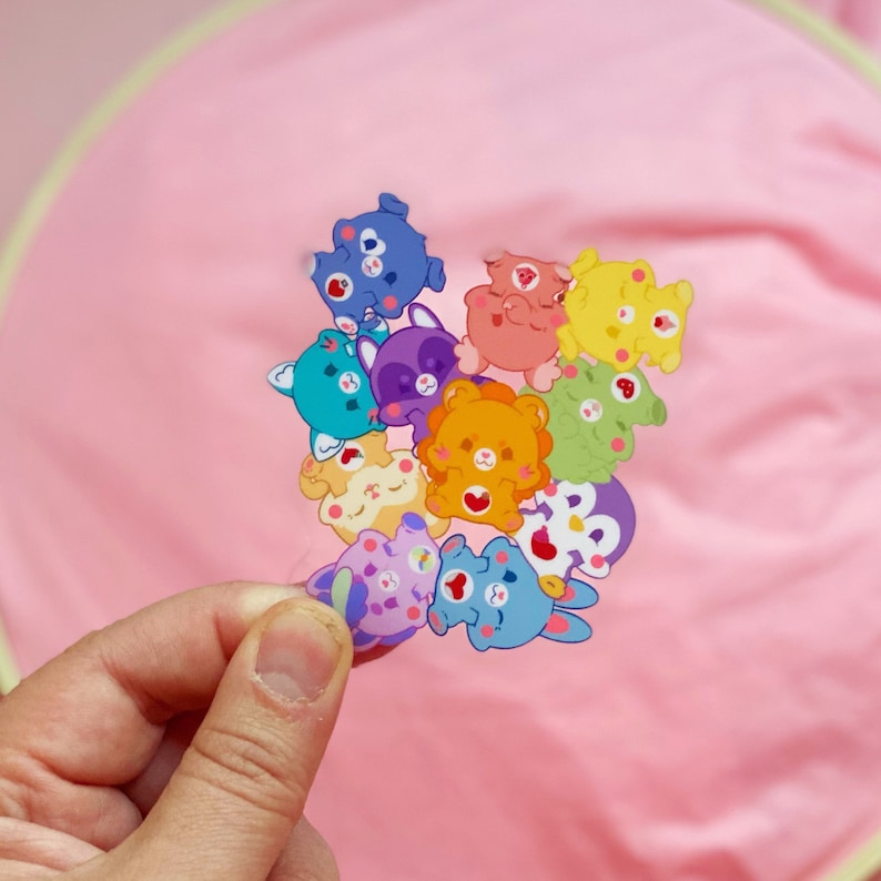 May include: A set of colorful cartoon animal stickers with different expressions. The stickers are arranged in a circle and feature a variety of animals, including a cat, a dog, a bear, a rabbit, and a raccoon.