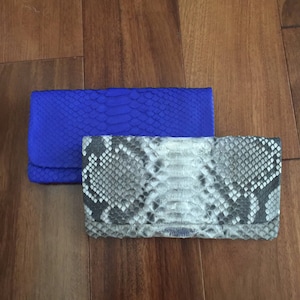 May include: Two clutches, one blue and one with a snakeskin pattern.