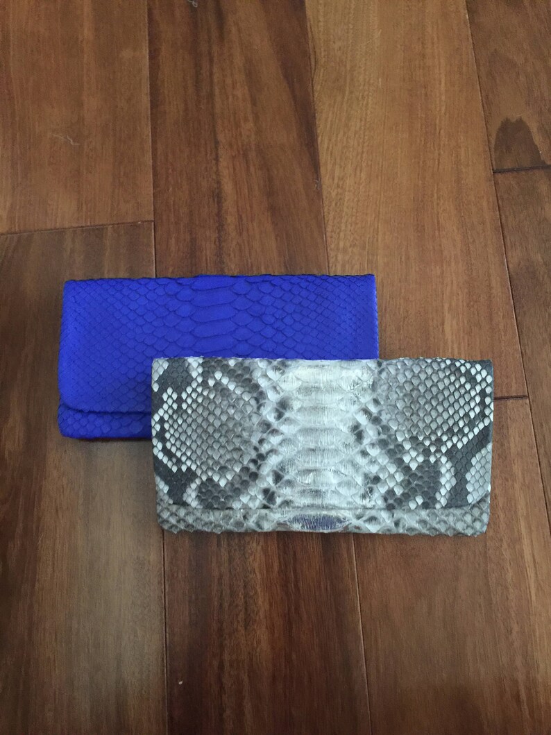May include: Two clutches, one blue and one with a snakeskin pattern.