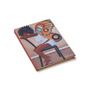 May include: A colorful journal cover featuring a painting of a woman with butterfly wings sitting on a chair. The woman is wearing a white top and has dark skin. The butterfly wings are orange, brown, and blue.
