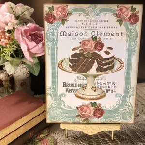 May include: A vintage advertisement for Maison Cl&eacute;ment, a shop specializing in ice cream, particularly for baptisms. The ad features a decorative design with roses and a plate of chocolate cake. The text reads "Salon de Consommation Glaces Sp&eacute;cialit&eacute; Pour Bapt&ecirc;mes Maison Cl&eacute;ment Rue Courte 3 et 5 Maiso BRUXELLES ANVE d&eacute;tail: e Neuve N&ordm; 161 Royale N. 74 N&deg; 84."