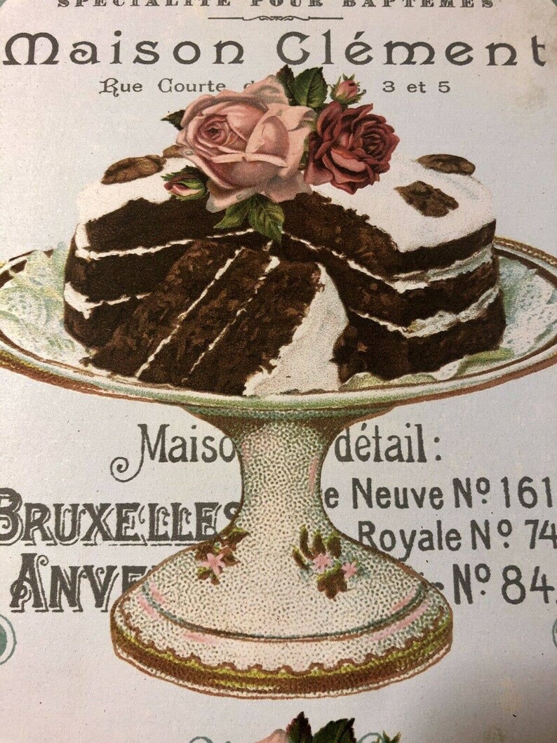 May include: A multi-layered chocolate cake with white frosting and a decorative arrangement of pink roses on top. The cake is on a white cake stand with a gold trim. The text "Maison Cl&eacute;ment" is visible at the top of the image.