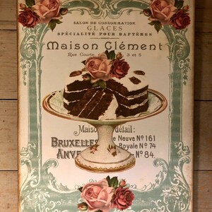 May include: A vintage advertisement for Maison Cl&eacute;ment, a bakery specializing in ice cream and cakes. The ad features a two-tiered cake with chocolate frosting and a decorative rose on top. The text reads "Salon de Consommation Glaces Specialite pour Bapteme Maison Clement Rue Courte 3 et 5 Maiso Bruxelles Anve detail: e Neuve No 161 Royale No 74 No 84."