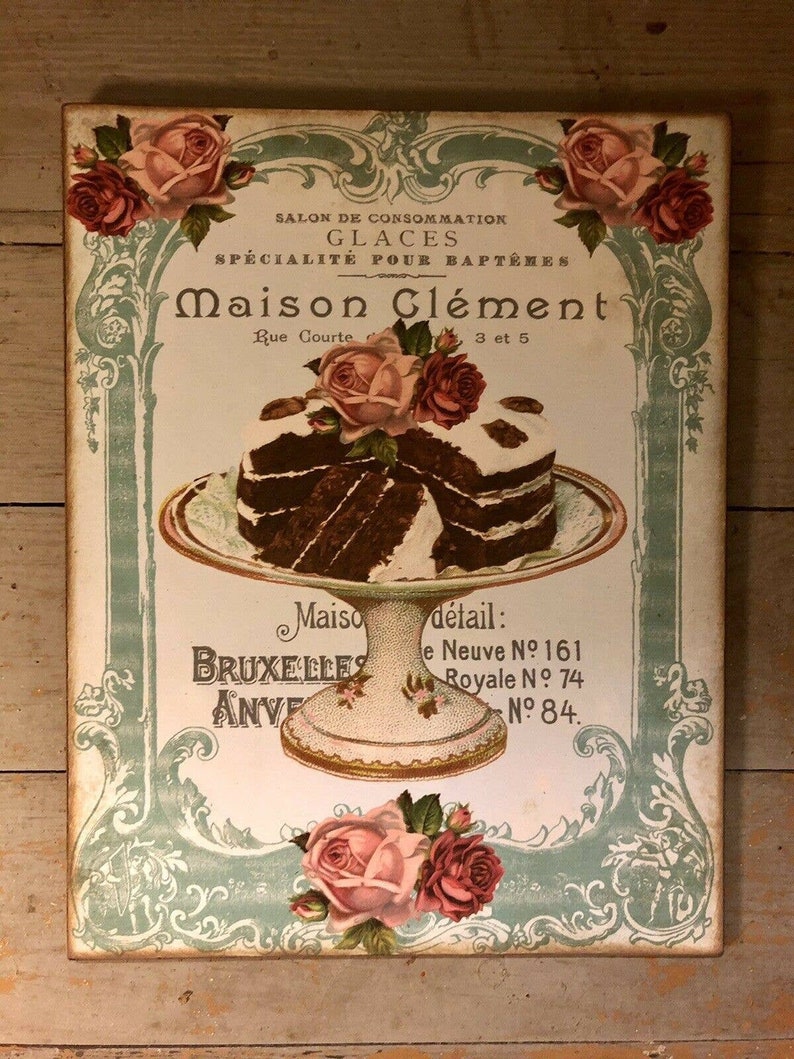 May include: A vintage advertisement for Maison Cl&eacute;ment, a bakery specializing in ice cream and cakes. The ad features a two-tiered cake with chocolate frosting and a decorative rose on top. The text reads "Salon de Consommation Glaces Specialite pour Bapteme Maison Clement Rue Courte 3 et 5 Maiso Bruxelles Anve detail: e Neuve No 161 Royale No 74 No 84."
