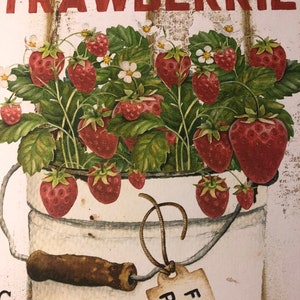 Może przedstawiać: Biały znak z tekstem "Farm to Market Strawberries" w czarnych i czerwonych literach. Białe wiadro z brązowym uchwytem i etykietą z napisem "Fresh Picked" jest wypełnione czerwonymi truskawkami i zielonymi liśćmi.