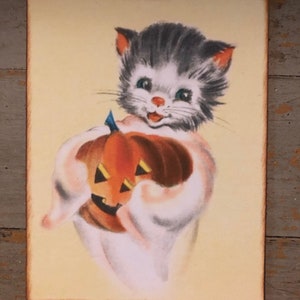 Pu&ograve; includere: Un'illustrazione vintage di Halloween di un gattino grigio e bianco che tiene una zucca arancione intagliata. Il gattino indossa un costume da fantasma bianco e ha un'espressione felice sul viso.