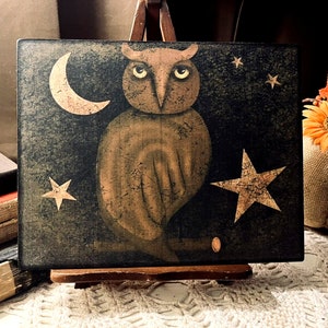 Pu&ograve; includere: Un cartello in legno dipinto a mano con un gufo marrone appollaiato su un ramo, circondato da una luna crescente e stelle. Lo sfondo &egrave; verde scuro con una finitura usurata.