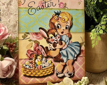May include: A vintage-style Easter card featuring a girl in a blue dress holding a brown bunny. The card has a pink and yellow background with a blue and green patterned ribbon. The text "Happy Easter!" is written in cursive at the top of the card.