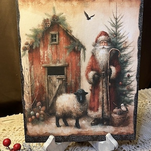 May include: A vintage-style Christmas scene with Santa Claus standing next to a Christmas tree, a red barn, and a white sheep. The scene is painted on a wooden plaque with a black border and a distressed look.