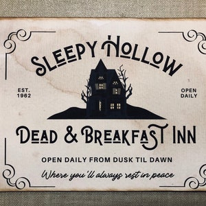May include: A vintage-style sign with the text "Sleepy Hollow Dead & Breakfast Inn" in a spooky font. The sign features a silhouette of a haunted house with windows and a black background. The text "Est. 1962" and "Open Daily" are also included.
