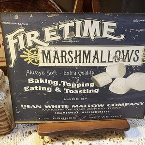 May include: Vintage Firetime Marshmallows sign. The sign is dark blue with white lettering and features the brand name and product description. The sign also includes an image of marshmallows and the text "Always Soft - Extra Quality".