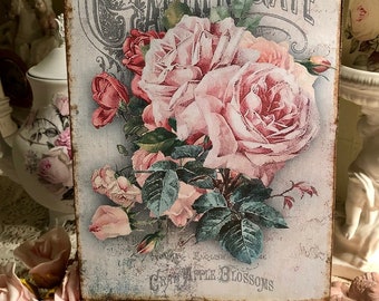 May include: A vintage-style sign with a floral design featuring pink roses and green leaves. The sign reads "Garden Gate" and "English Rose Cry Apple Blossoms".