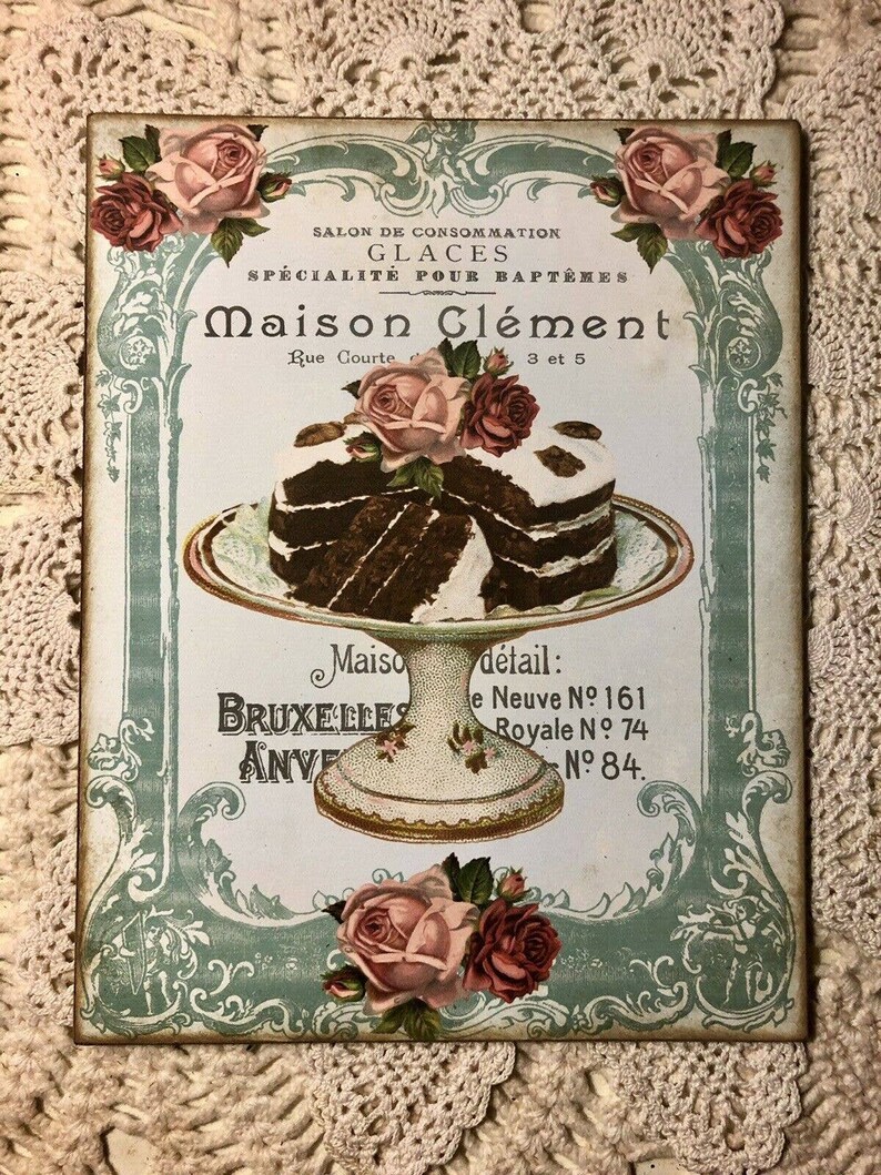 May include: Vintage advertisement for Maison Cl&eacute;ment, a shop specializing in ice cream for baptisms. The ad features a decorative border with roses and a plate of chocolate cake. The text reads "Salon de Consommation Glaces Specialit&eacute; pour Bapt&ecirc;mes Maison Cl&eacute;ment Rue Courte 3 et 5 Maiso BRUXELLES ANVE detail: e Neuve N&ordm; 161 Royale N&deg; 74 N&deg; 84."