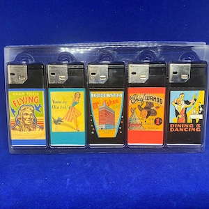 Może przedstawiać: Zestaw sześciu osłon zapalniczek w stylu vintage z kolorowymi ilustracjami. Osłony przedstawiają obrazy pilota, psa, hotelu, kowboja i pary tańczącej. Tekst na osłonach zawiera "Keep Them Flying", "Young Dog - Old Trick", "Coffee Shop Mc. Tehee Hotel", "Big Chief Wahoo" i "Dining & Dancing".