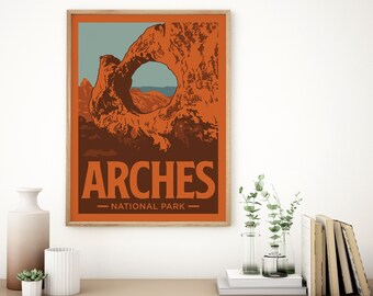 May include: A framed art print featuring a stylized illustration of Arches National Park. The artwork showcases a large orange rock formation with a natural arch, set against a blue sky and brown foreground. The word "ARCHES" is prominently displayed.